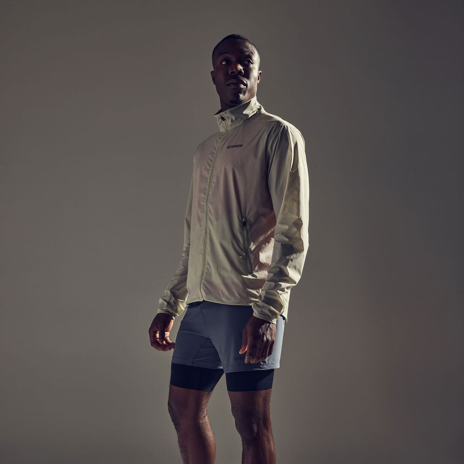 Front view of a model wearing the GOREWEAR Men's Concurve Windbreaker in the Tech Beige colourway. Model is also wearing shorts. (8604901965986)