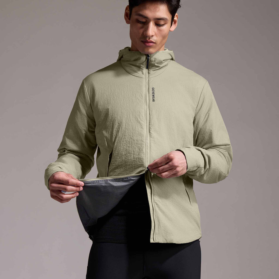 Front view of a model wearing the GOREWEAR Men's Concurve WINDSTOPPER Insulated Hooded Jacket in the Tech Beige colourway. (8751767945378)