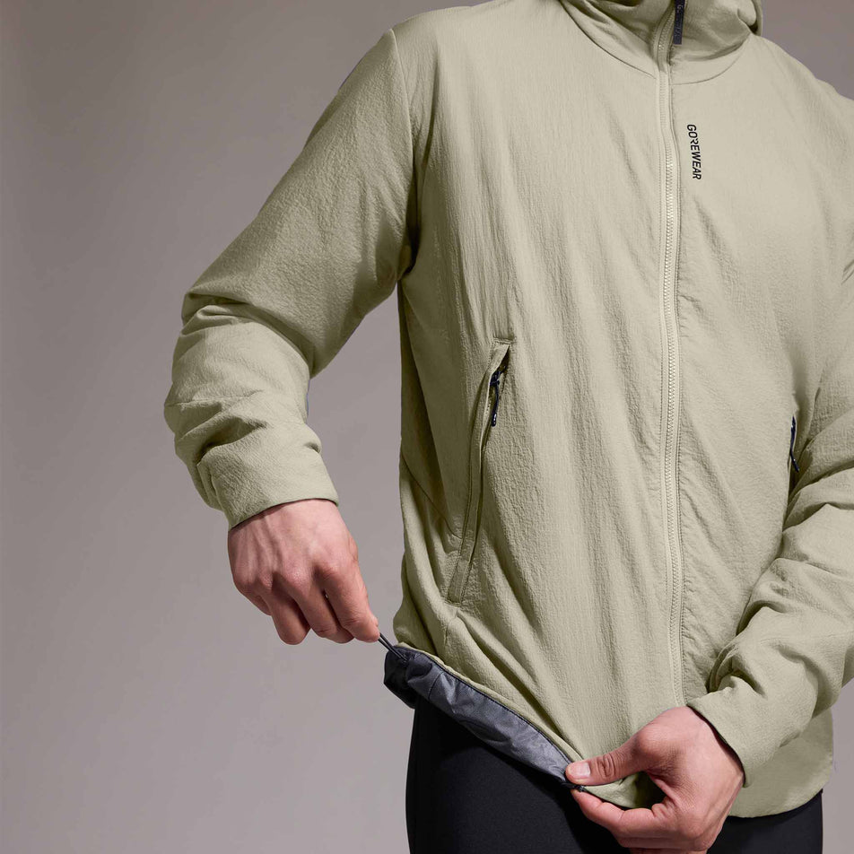 Front view of a model wearing the GOREWEAR Men's Concurve WINDSTOPPER Insulated Hooded Jacket in the Tech Beige colourway. (8751767945378)
