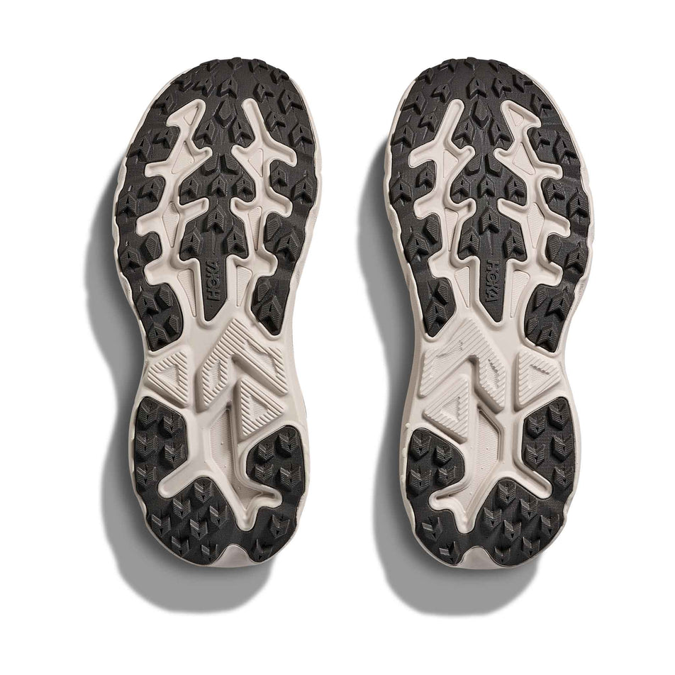 The outsoles of a pair of HOKA Women's Challenger 8 Running Shoes in the Stucco/Asphalt Grey colourway.