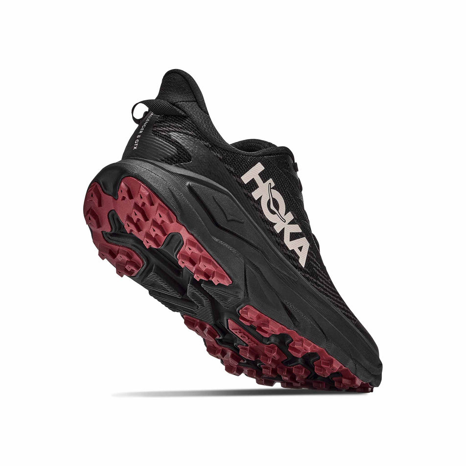 Lateral - and outsole - view of the right shoe from a pair of HOKA Women's Challenger 8 GTX Trail Running Shoes in the Black/Varsity Burgundy colourway.