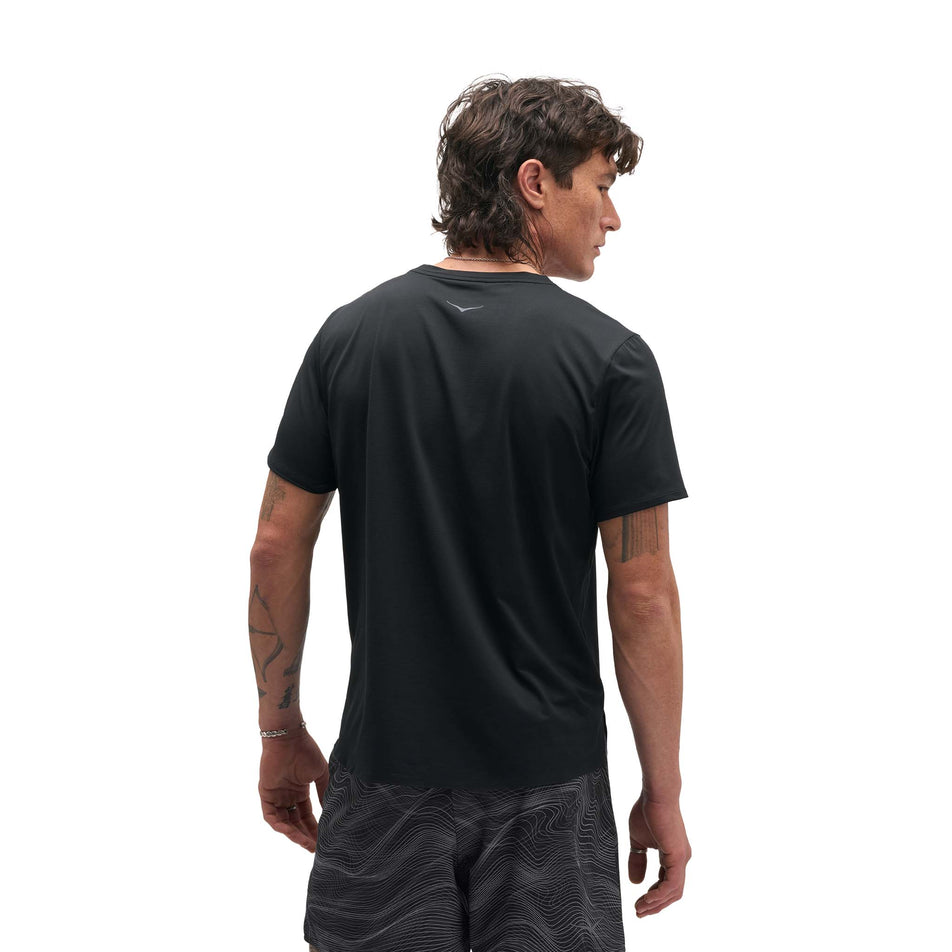 Back view of a model wearing the HOKA Men's Everyrun Short Sleeve in the Black colourway.