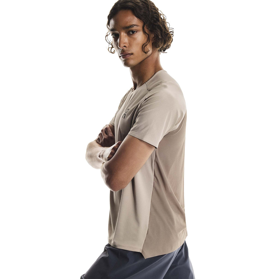 Side view of a model wearing the On Men's Performance-T in the Desert/Cinder colourway.