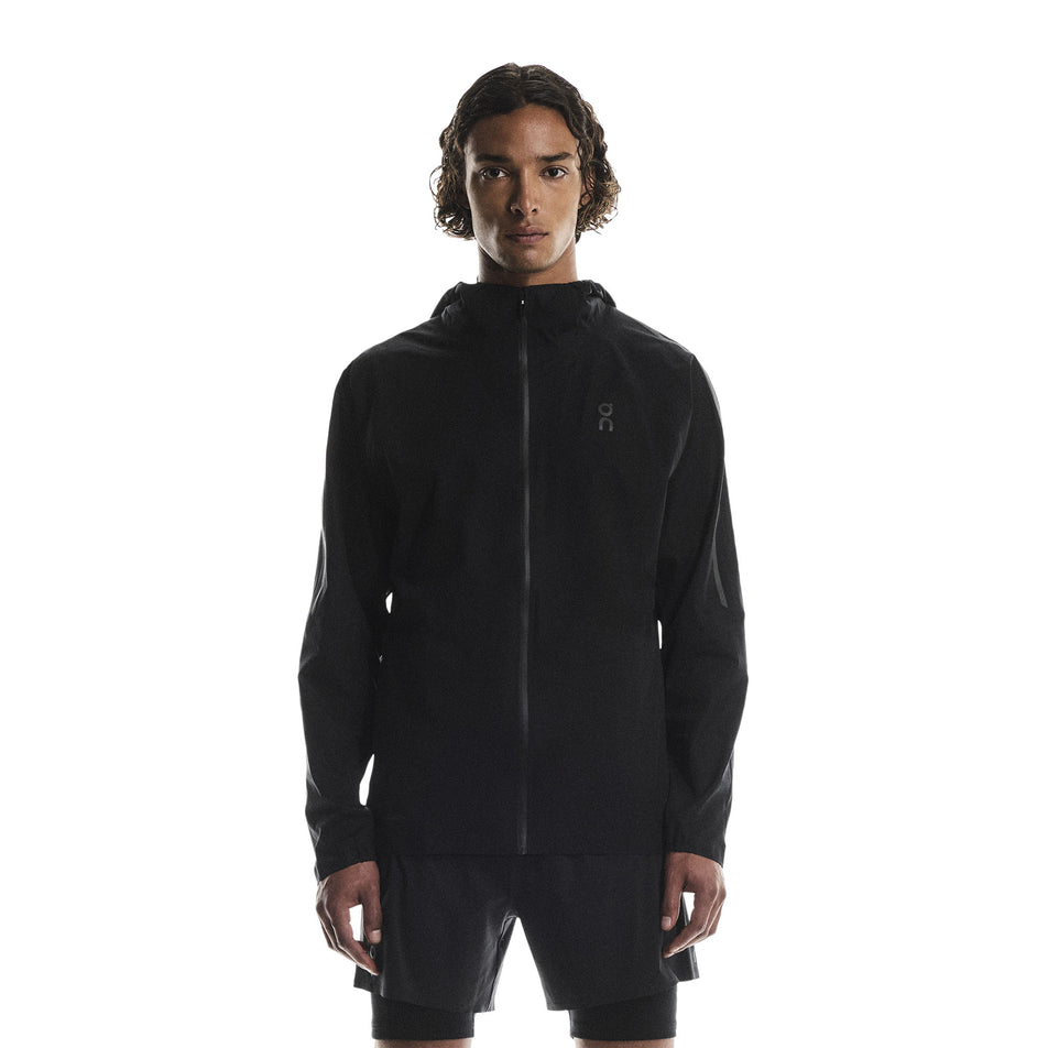Front view of a model wearing the On Men's Performance Waterproof Jacket in the Black colourway. (8790101819554)