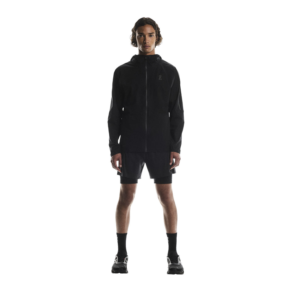 Front view of a model wearing the On Men's Performance Waterproof Jacket in the Black colourway. (8790101819554)