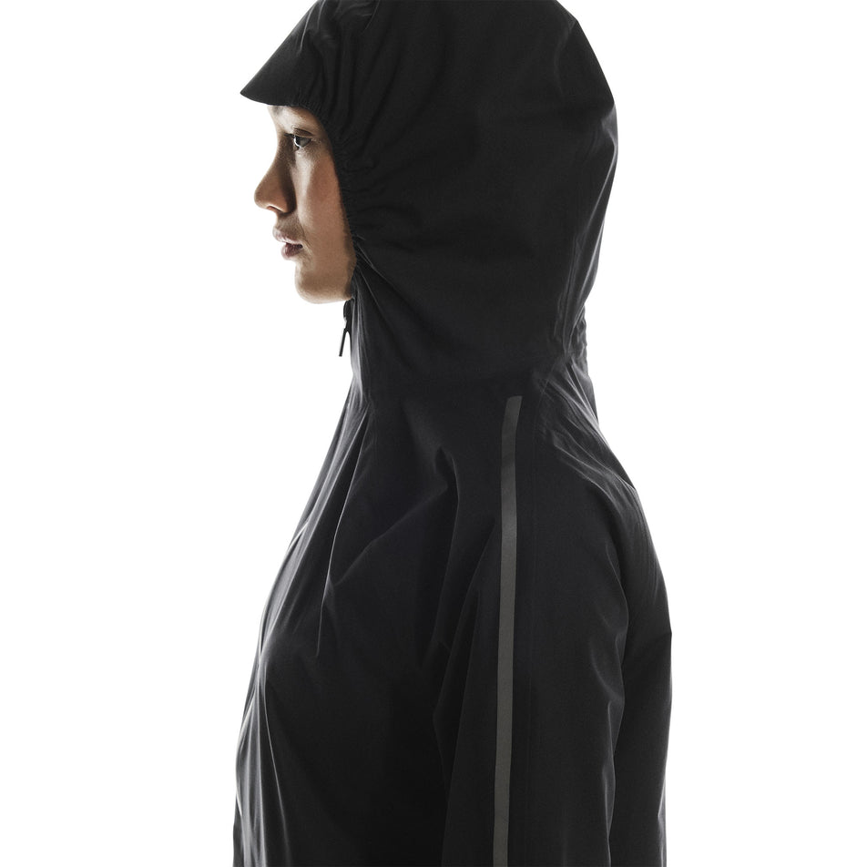 Side view of a model wearing the On Women's Performance Waterproof Jacket in the Black colourway. (8790002696354)