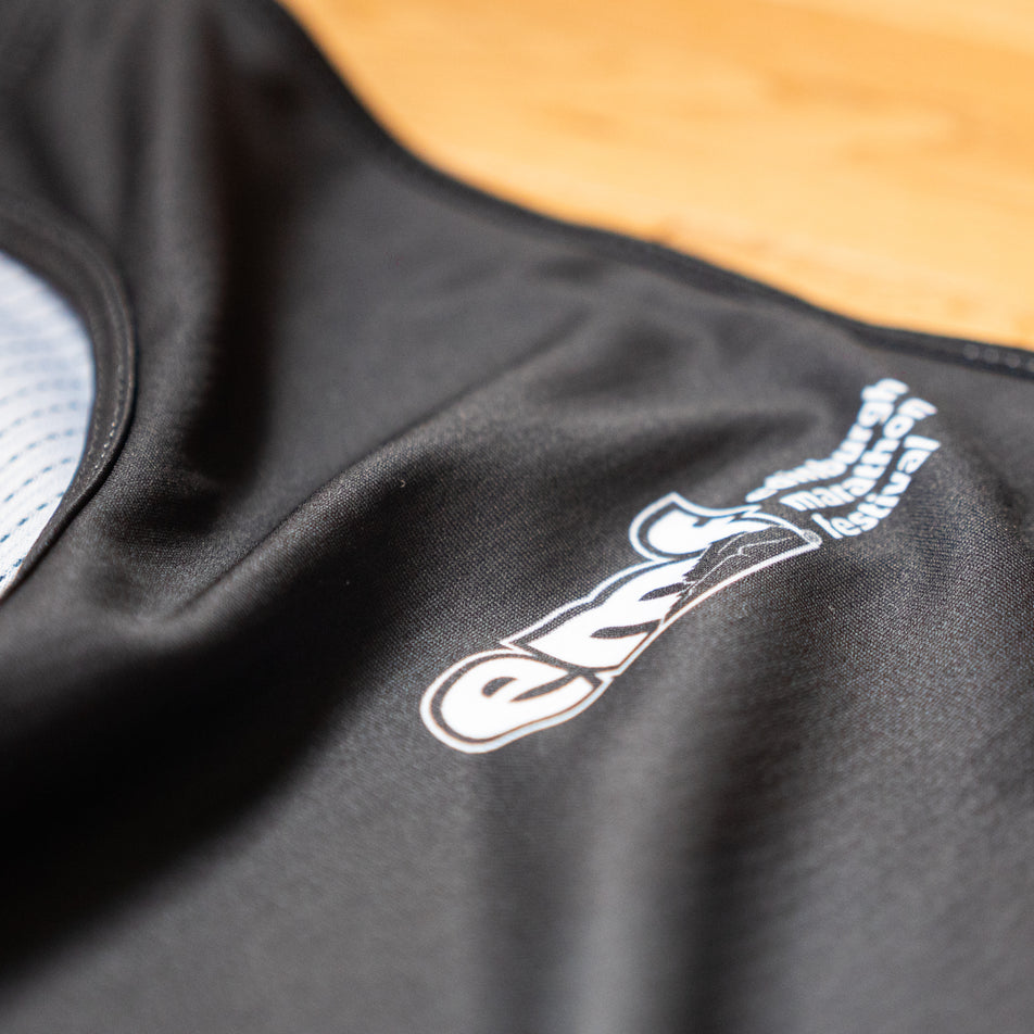 Close-up view of the EMF logo on the EMF Official Licensed Merchandise | Pressio Men's Prevail Singlet in the Black/Stone colourway.