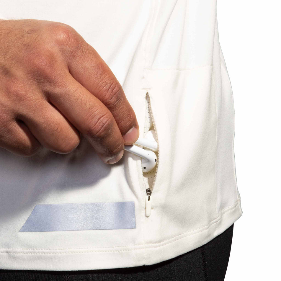 Close-up view of the zippered pocket on the Brooks Men's Run Visible 1/2 Zip 2.0 in the Ecru/Fluoro Flash/Black colourway. (8499413188770)