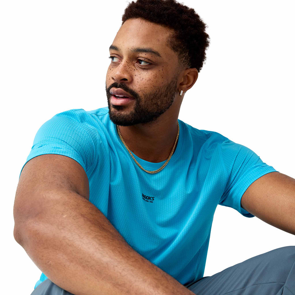 Angled view of a model wearing the Brooks Men's High Point Short Sleeve 2.0 in the Blazing Blue/Atomic Blue colourway.