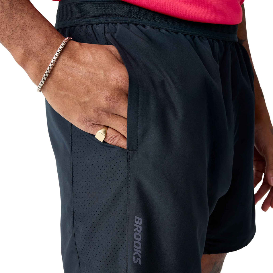 A model demonstrating the hand pocket on the side of the Brooks Men's Dash 2-in-1 Shorts in the Black colourway.