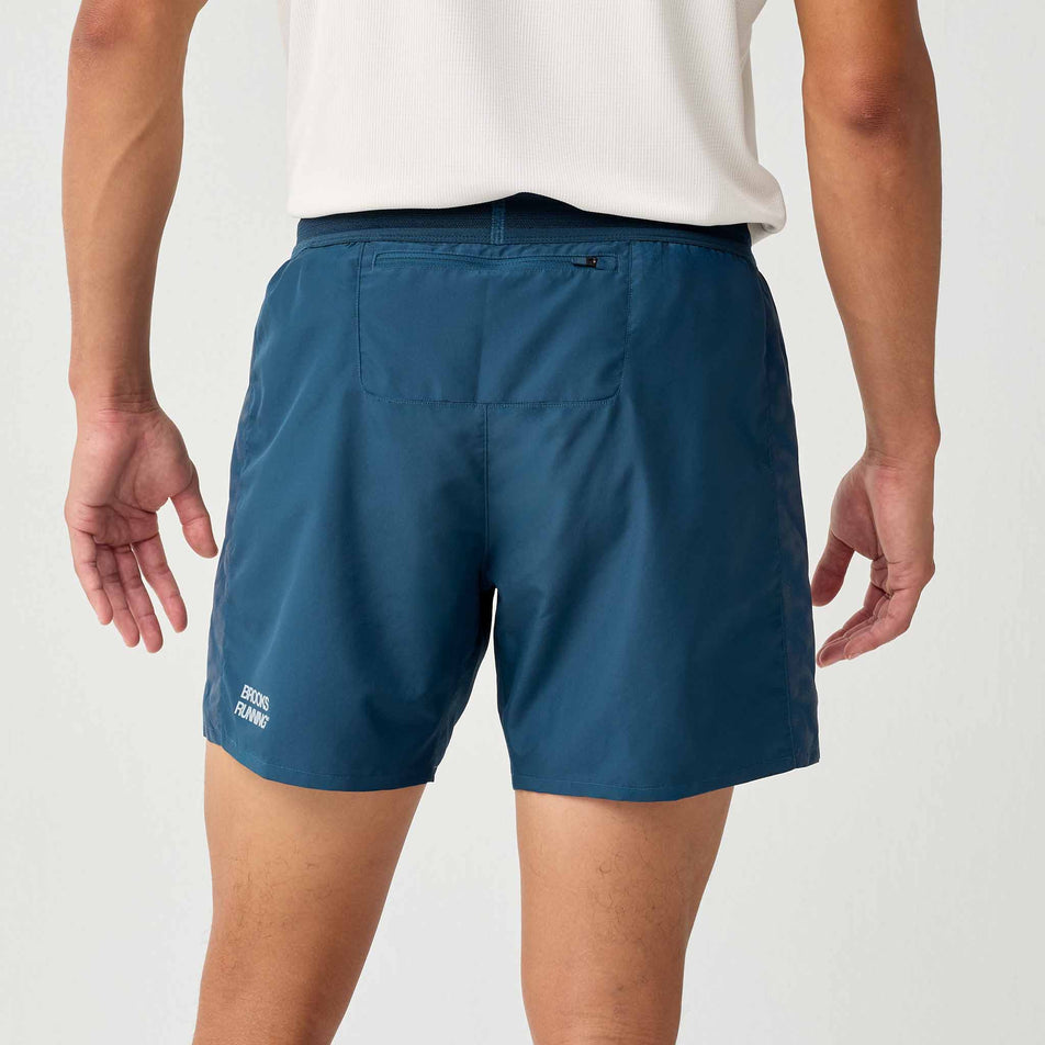 Back view of a model wearing the Brooks Men's Dash Reflective Short in the Reflective Wordmark Indigo colourway.