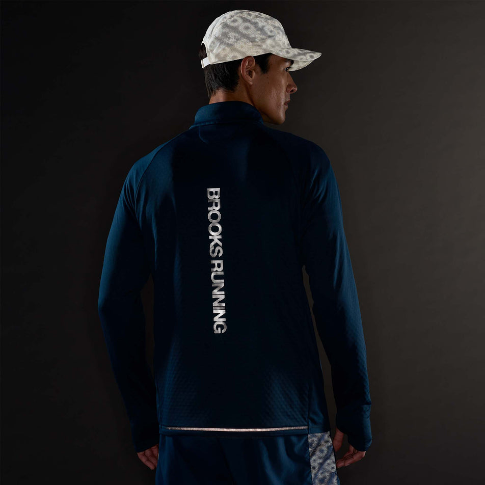 The reflective graphic on the back of the Brooks Men's Thermal Reflective 1/2 Zip in the Reflective Wordmark Indigo colourway.