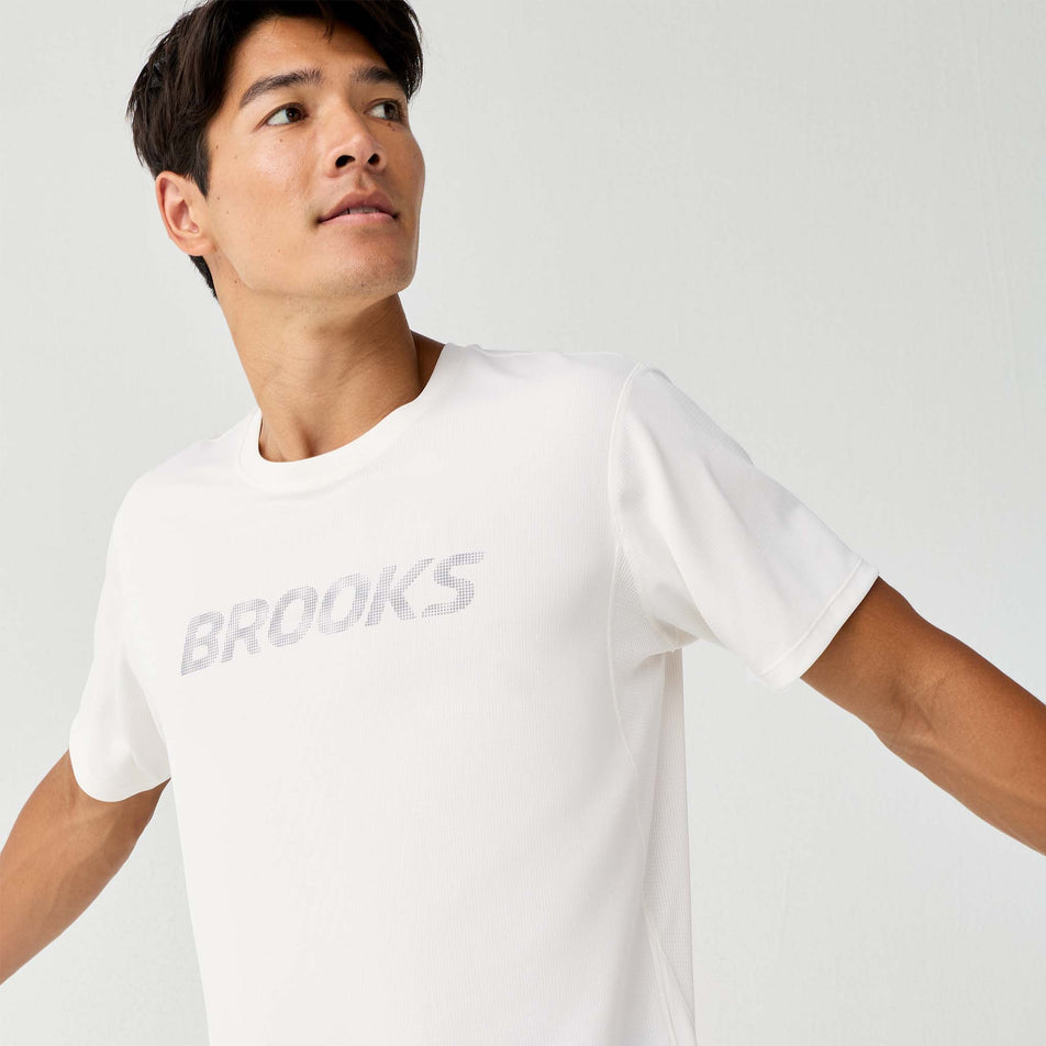 Front view of a model wearing the Brooks Men's Dash Reflective Short Sleeve in the Bone/Reflective colourway.