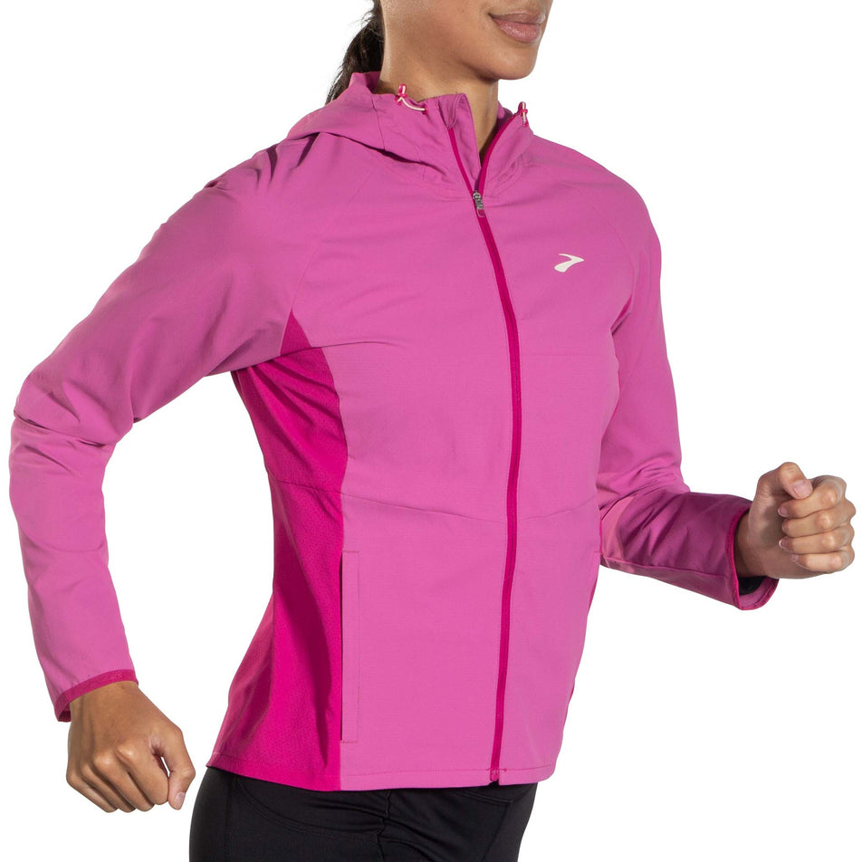 Angled front view of a model wearing a Brooks Women's Canopy Jacket in the Frosted Mauve/Mauve colourway. Model is in a running pose.  (8007491748002)