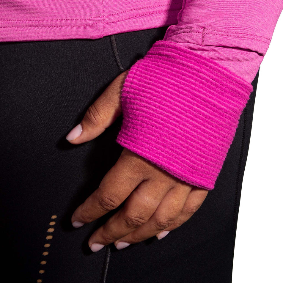 A model demonstrating that there are thumb holes in the ends of the sleeves of a Brooks Women's Notch Thermal Hoodie 2.0 in the Heather Frosted Mauve colourway. And that the fabric can be pulled over your hands. (8007496007842)