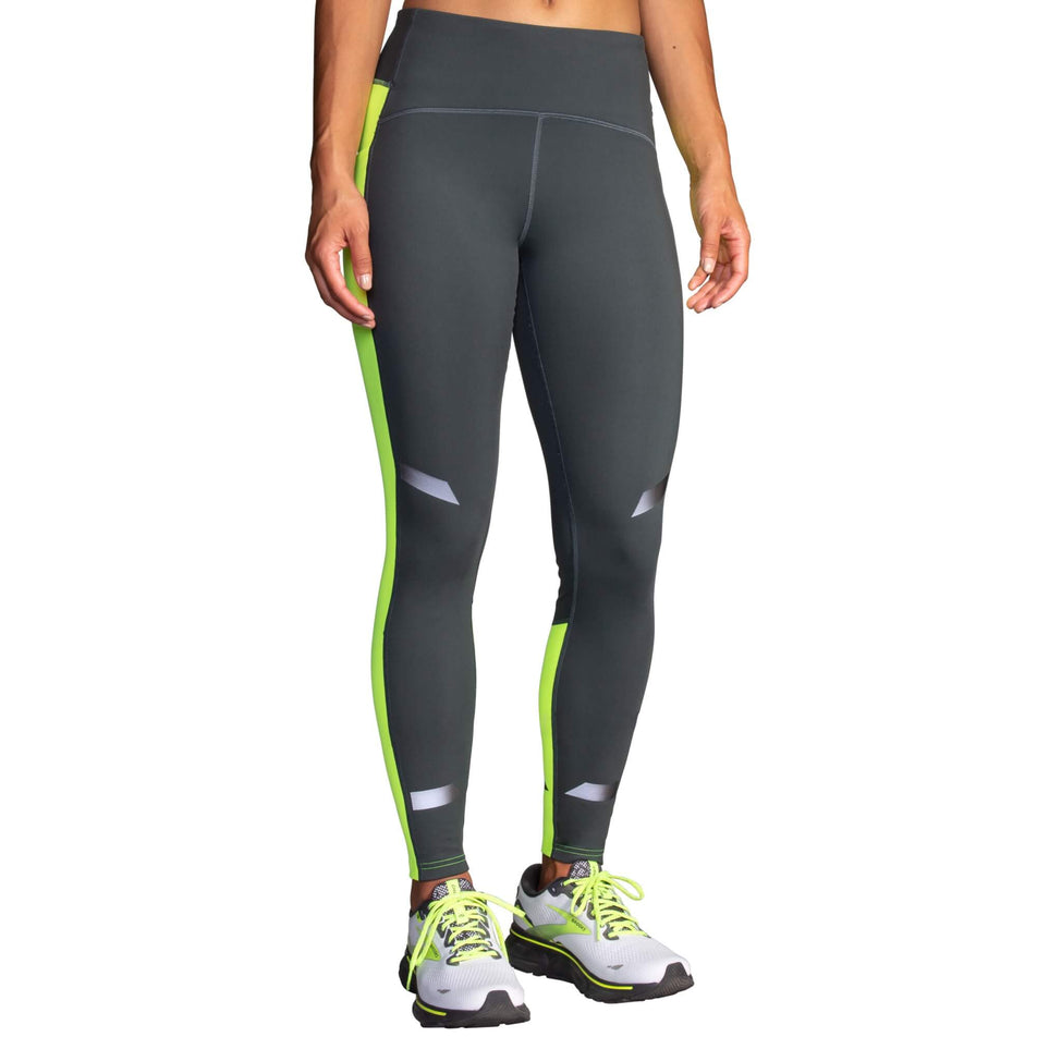 Front view of a model wearing a pair of Brooks Women's Run Visible Thermal Tights in the Asphalt/Nightlife colourway. Model is also wearing a pair of Brooks running shoes. (8065569194146)