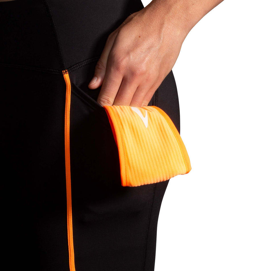 Close-up view of the drop-in pocket on the left side of the Brooks Women's Run Visible Tight 2.0 in the Black/Fluoro Flash colourway. (8499453362338)