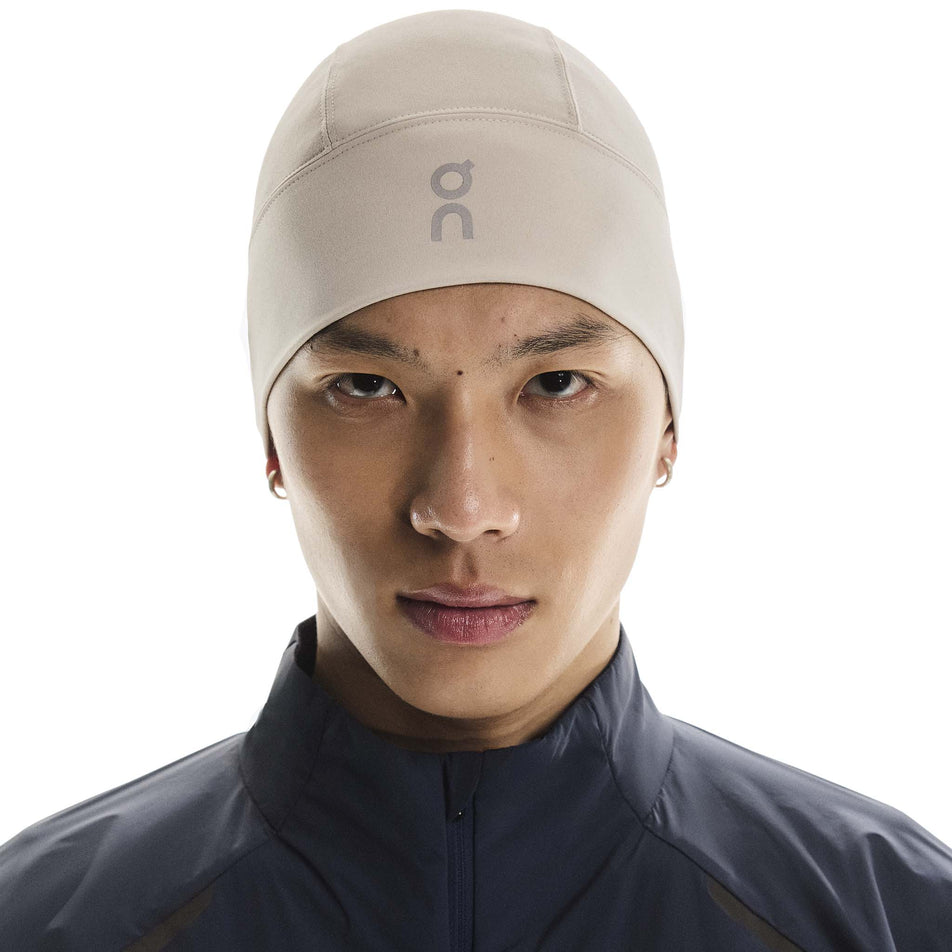 Front view of a model wearing the On Core Beanie in the Truffle colourway. (8717368000674)