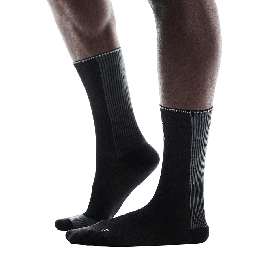 Side view of a model wearing a pair of On Unisex Performance Run Sock High in the Black/Eclipse colourway.