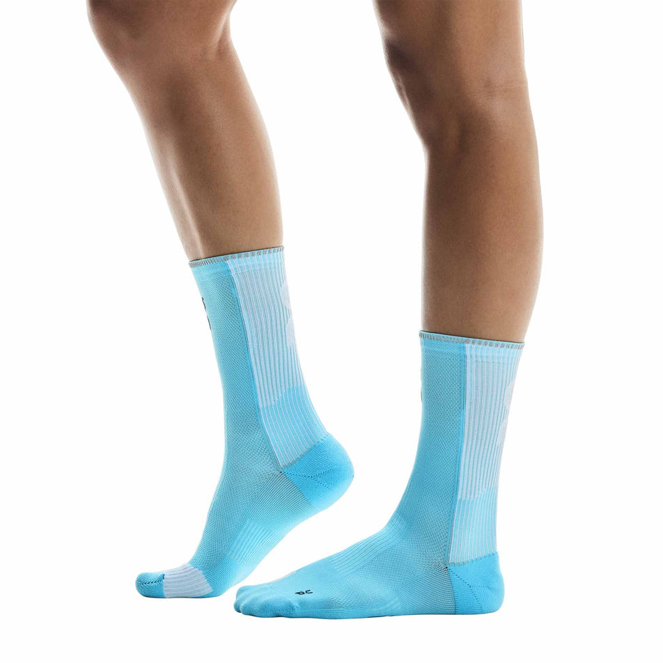 Side view of a model wearing the On Unisex Performance Run Sock High in the Horizon/White colourway. (8717340737698)