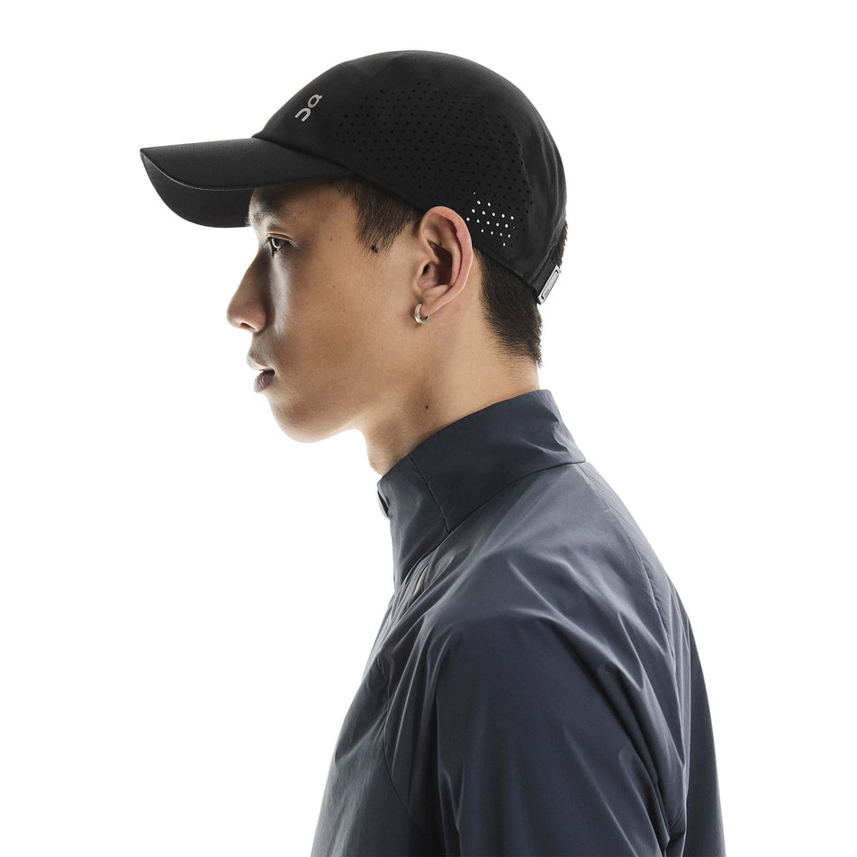 Side view of a model wearing the On Unisex Lightweight Cap in the Black colourway.