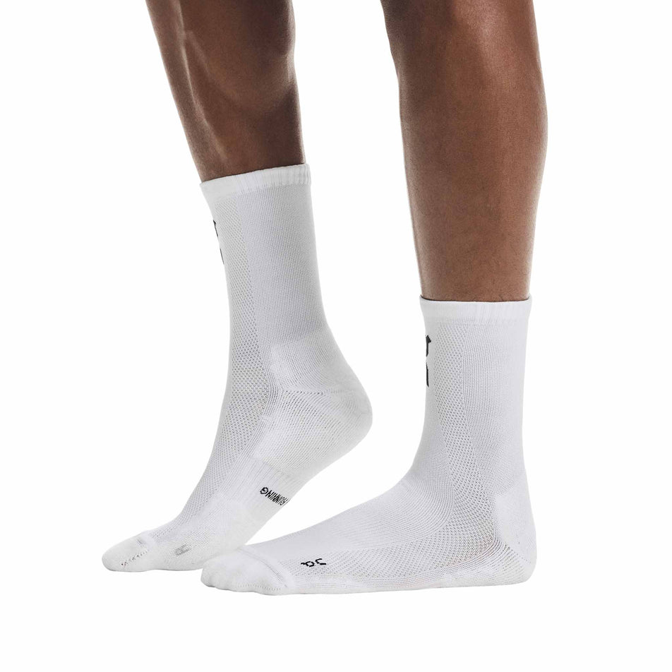 Side view of a model wearing a pair of On Unisex Core Run Sock High 2P in the White colourway.