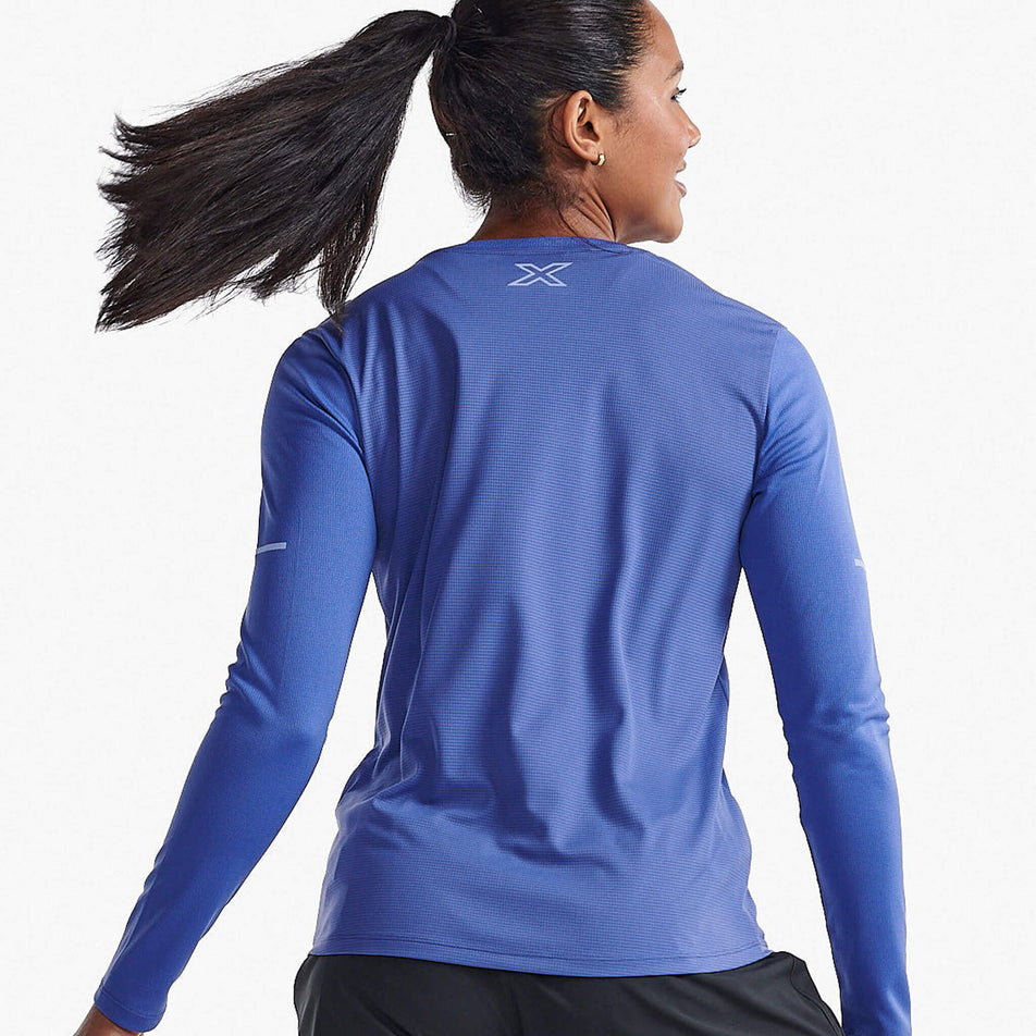 Back view of a model wearing a 2XU Women's Aero Long Sleeve in the Marlin/Hydrangea Reflective colourway (8250152550562)