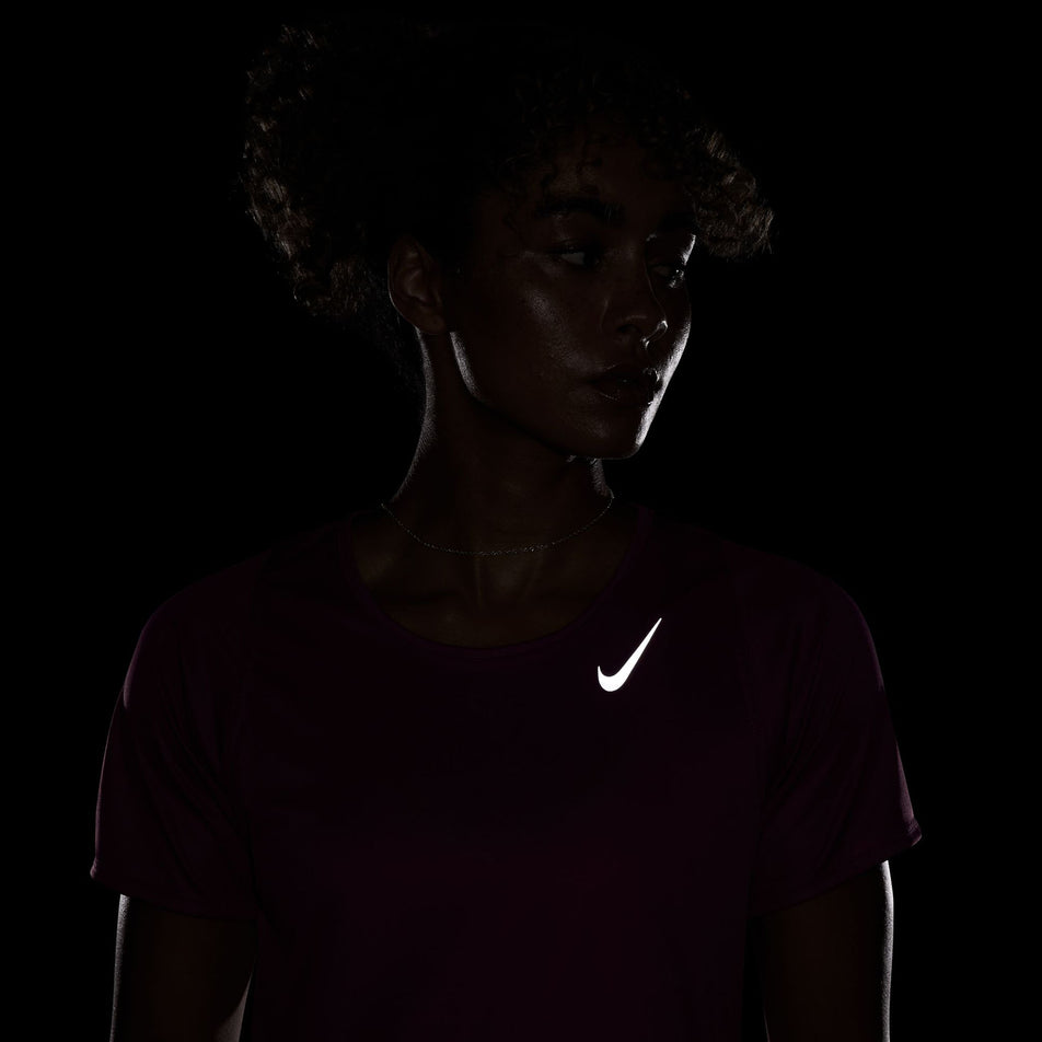 The reflective Nike SWOOSH on the front of a Nike Women's Dri-FIT Race Short-Sleeve Running Top. The top is being worn by a model. (8399187640482)
