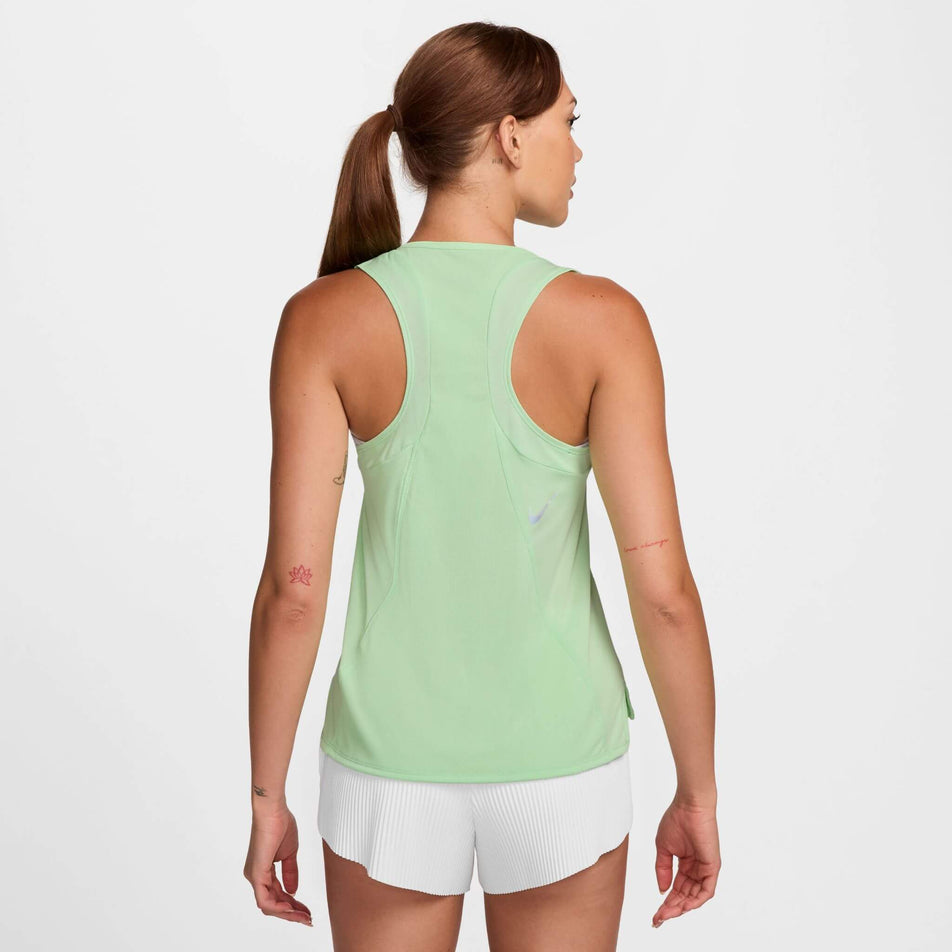 Back view of a model wearing a Nike Women's Dri-FIT Race Running Singlet in the Vapor Green/Reflective SIlv colourway. Model is also wearing Nike running shorts. (8399179022498)