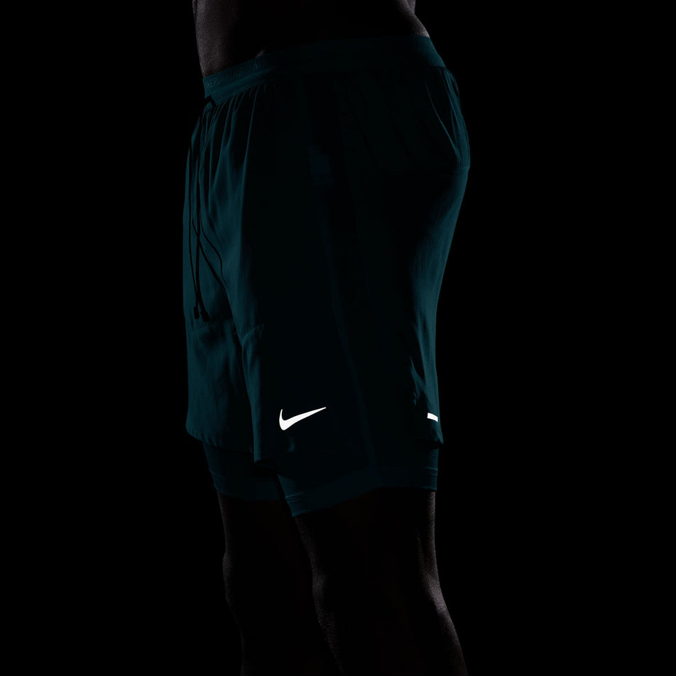 The reflective Nike SWOOSH on the front of a pair of Nike Men's Stride Dri-FIT 5