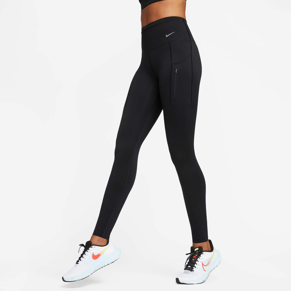 Front view of a model wearing a pair of Nike  Women's Go Firm-Support High-Waisted Full-Length Leggings with Pockets in the Black/Black colourway. Model is also wearing Nike running shoes. (8140163252386)