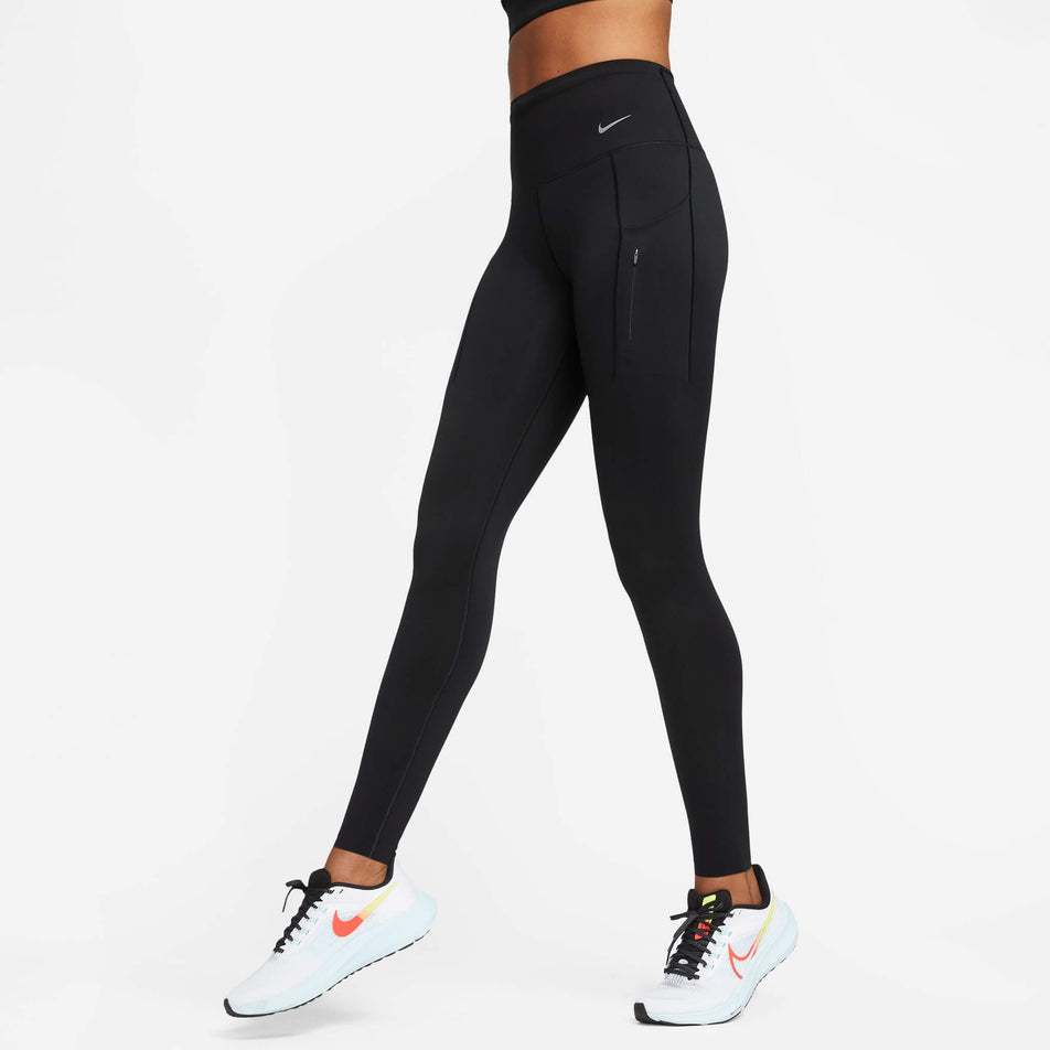 Front view of a model wearing a pair of Nike Women's Go Firm-Support High-Waisted Full-Length Leggings with Pockets in the Black/Black colourway. Model is also wearing Nike running shoes. (8140163252386)