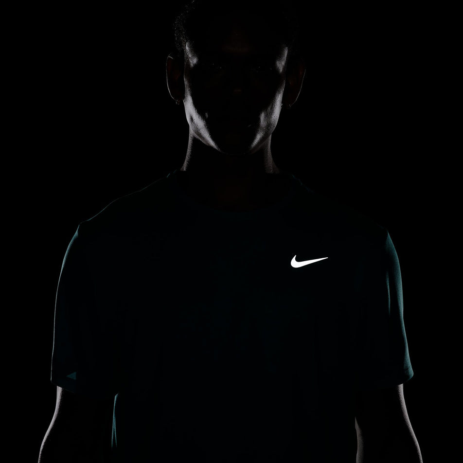 The reflective Nike SWOOSH on the front of the Nike Men's Miler Dri-FIT UV Short-Sleeve Running Top in the Dusty Cactus/Reflective Silver colourway. (8562855116962)