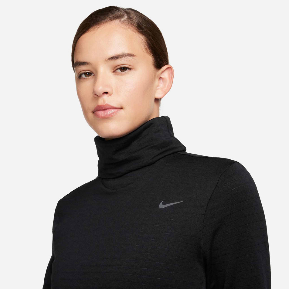 The front of the upper body of a model wearing a Nike Women's Swift Element Therma-FIT Turtleneck Running Top in the Black/Reflective Silver colourway. (8497637752994)