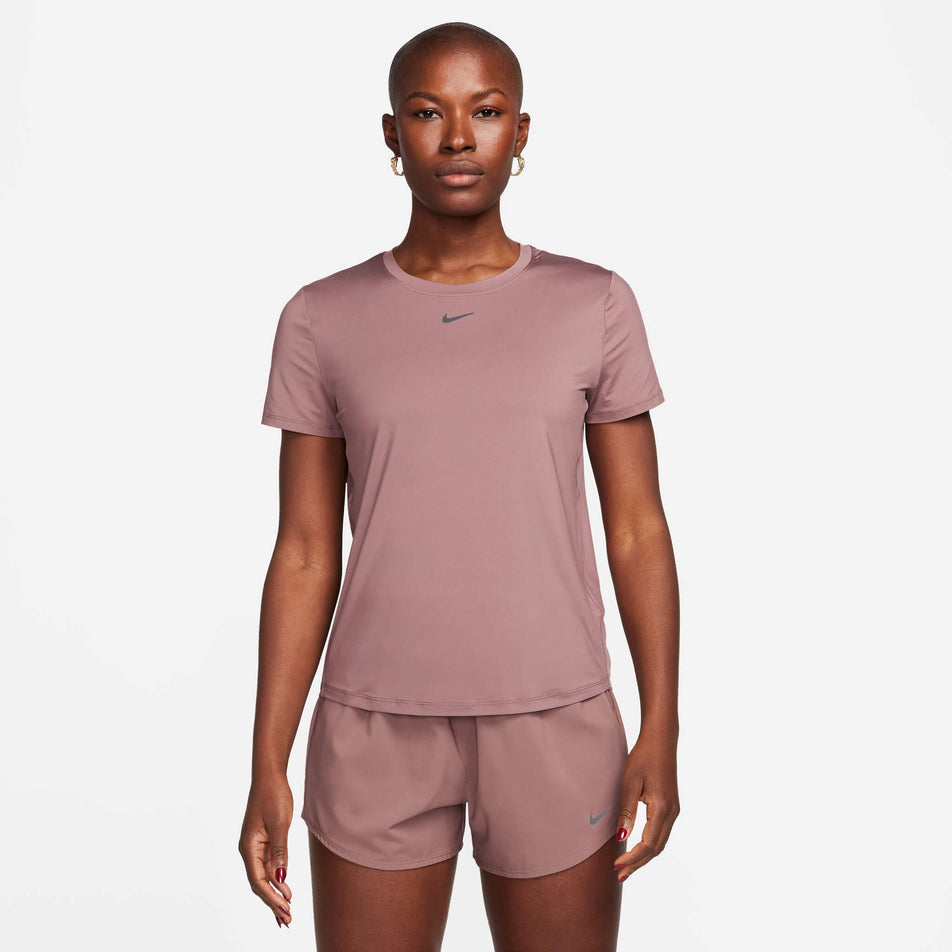 Front view of a model wearing a Nike Women's One Classic Dri-FIT Short-Sleeve Top in the Smokey Mauve/Black colourway. Model is also wearing Nike shorts.  (8140159713442)