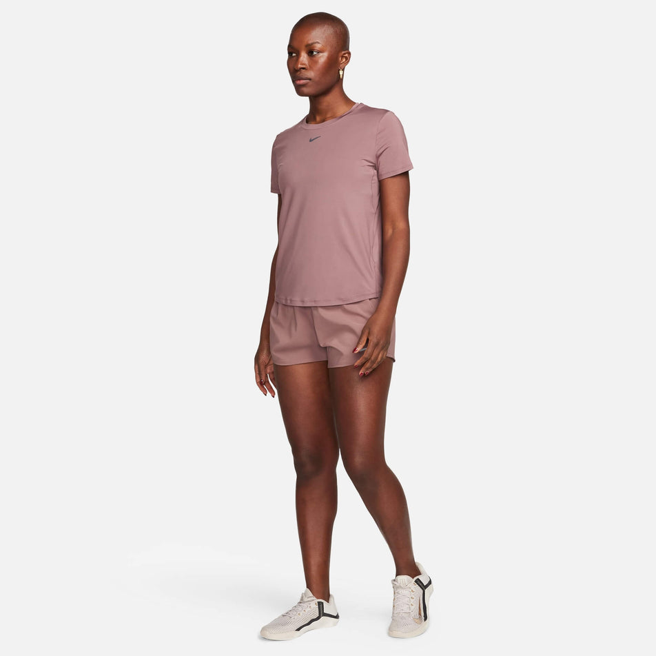 Front view of a model wearing a Nike Women's One Classic Dri-FIT Short-Sleeve Top in the Smokey Mauve/Black colourway. Model is also wearing Nike shorts and shoes. (8140159713442)