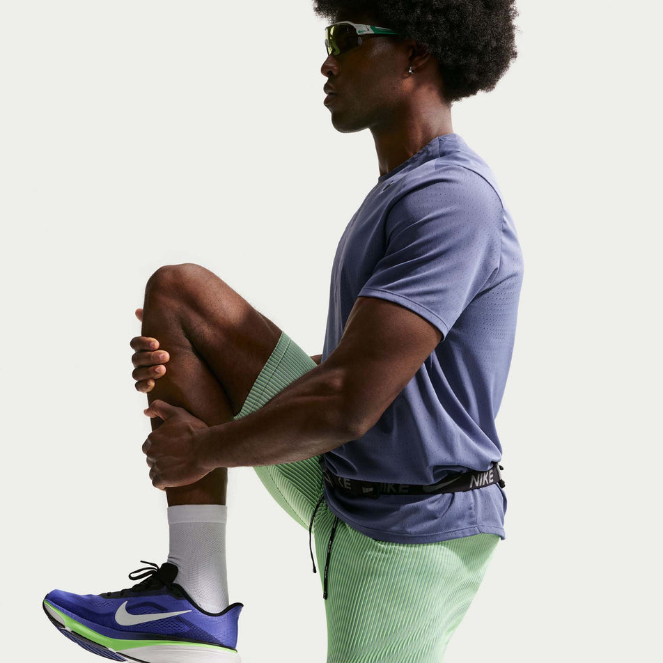 Side view of a model wearing the Nike Men's AeroSwift Dri-FIT ADV Running 1/2-Length Tights in the Lime Blast/Steam/Light Silver/Black colourway.