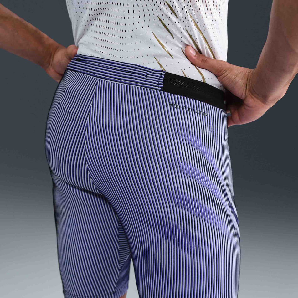 Back view of a model wearing the Nike Men's AeroSwift Dri-FIT ADV Running 1/2-Length Tights in the Vivid Purple/Black/Reflective colourway. (8692967669922)