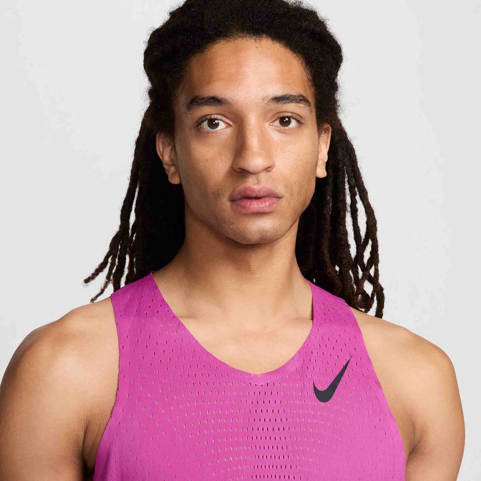 Close-up front view of a model wearing a Nike Men's AeroSwift Dri-FIT ADV Running Singlet in the Hot Fuchsia/Black colourway. Only the upper part of the singlet can be seen in the image.(8497704173730)