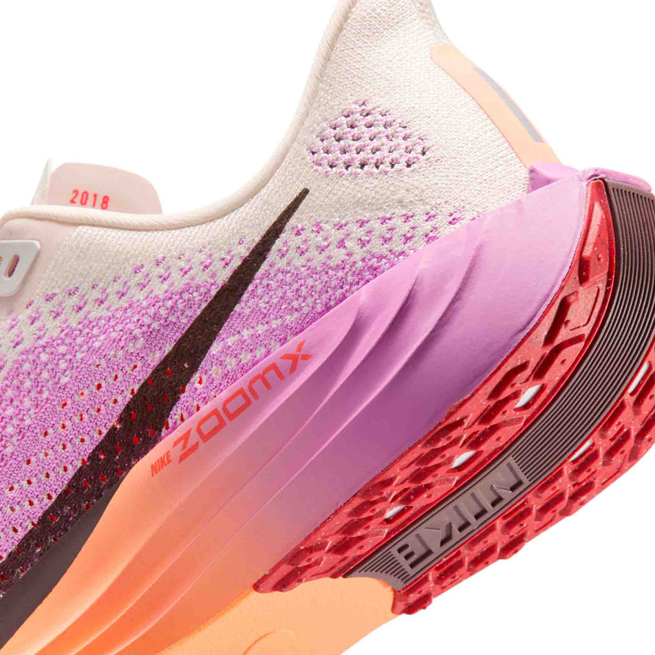 Close-up view of the rearfoot section of the left shoe from a pair of Nike Women's Pegasus Plus Road Running Shoes in the Chalk/Tattoo-Light Magenta-Bright Crimson colourway.