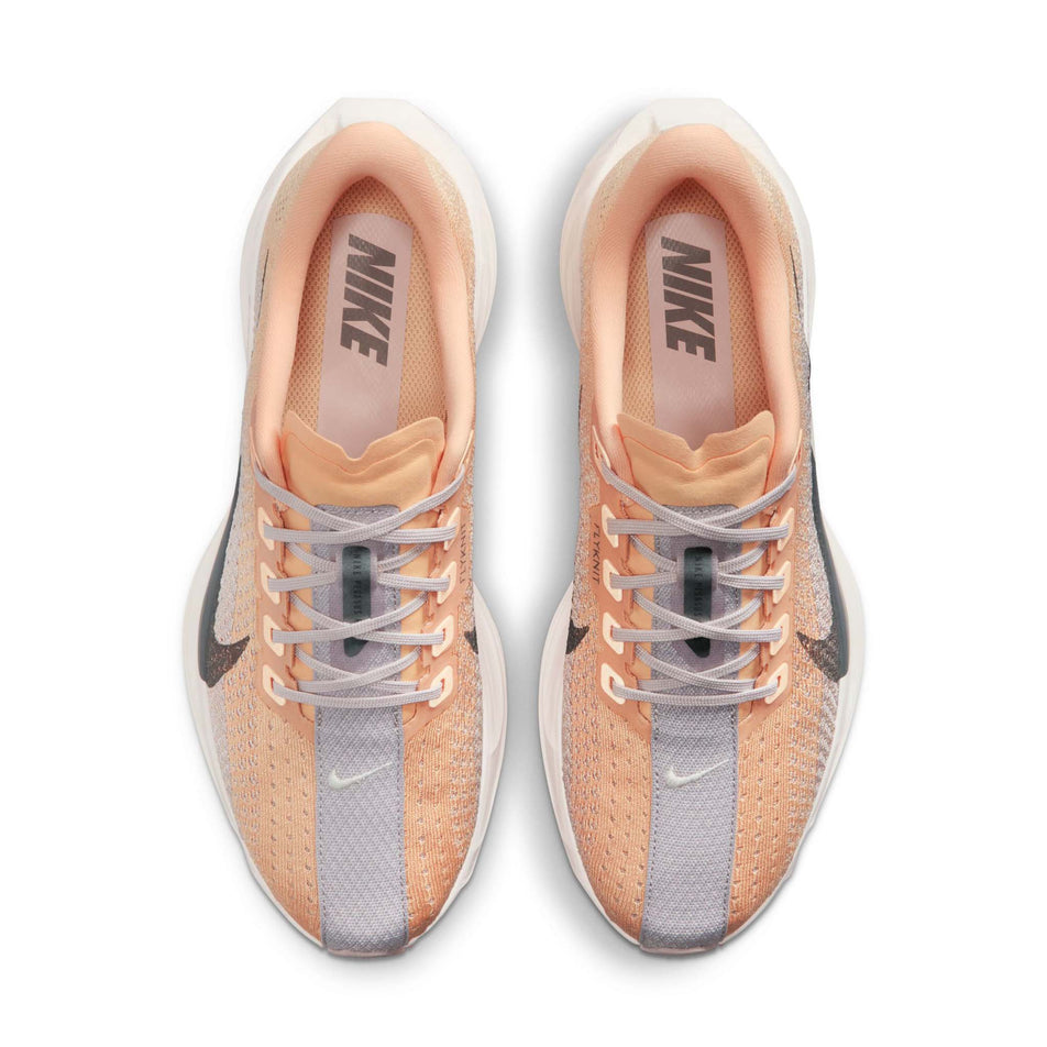 The uppers of a pair of Nike Women's Pegasus Plus Road Running Shoes in the Orange Chalk/Cave Stone-Platinum Violet colourway.