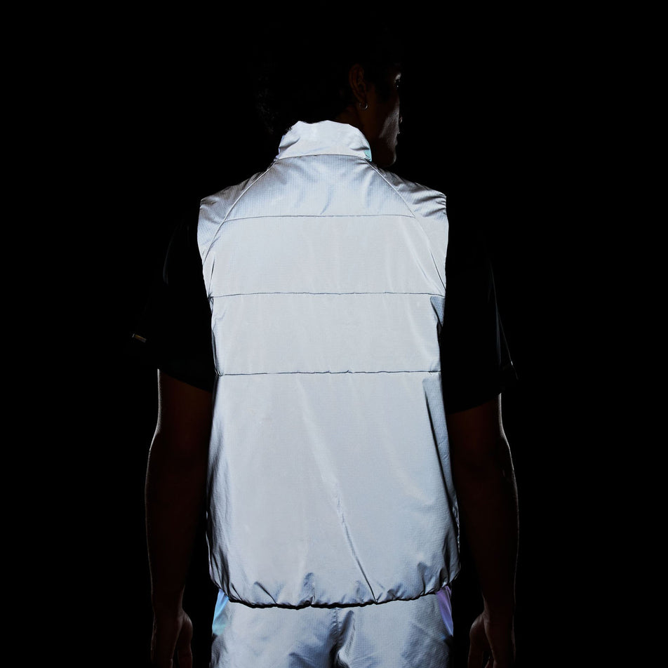 Back view of a model wearing the Nike Men's Therma-FIT Running Division ADV Running Vest in the dark, allowing the reflectivity to show. (8497736941730)