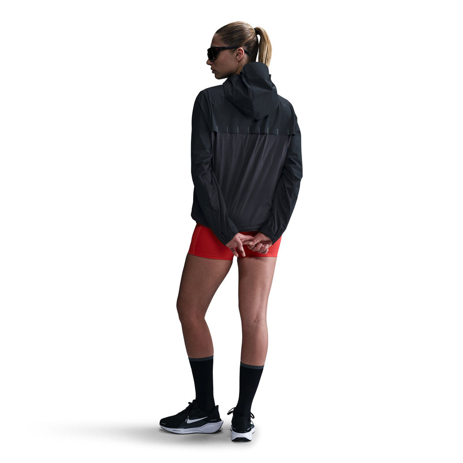 Back view of a model wearing the Nike Women's AeroSwift Aerogami Storm-FIT Running Jacket in the Black/Black colourway.