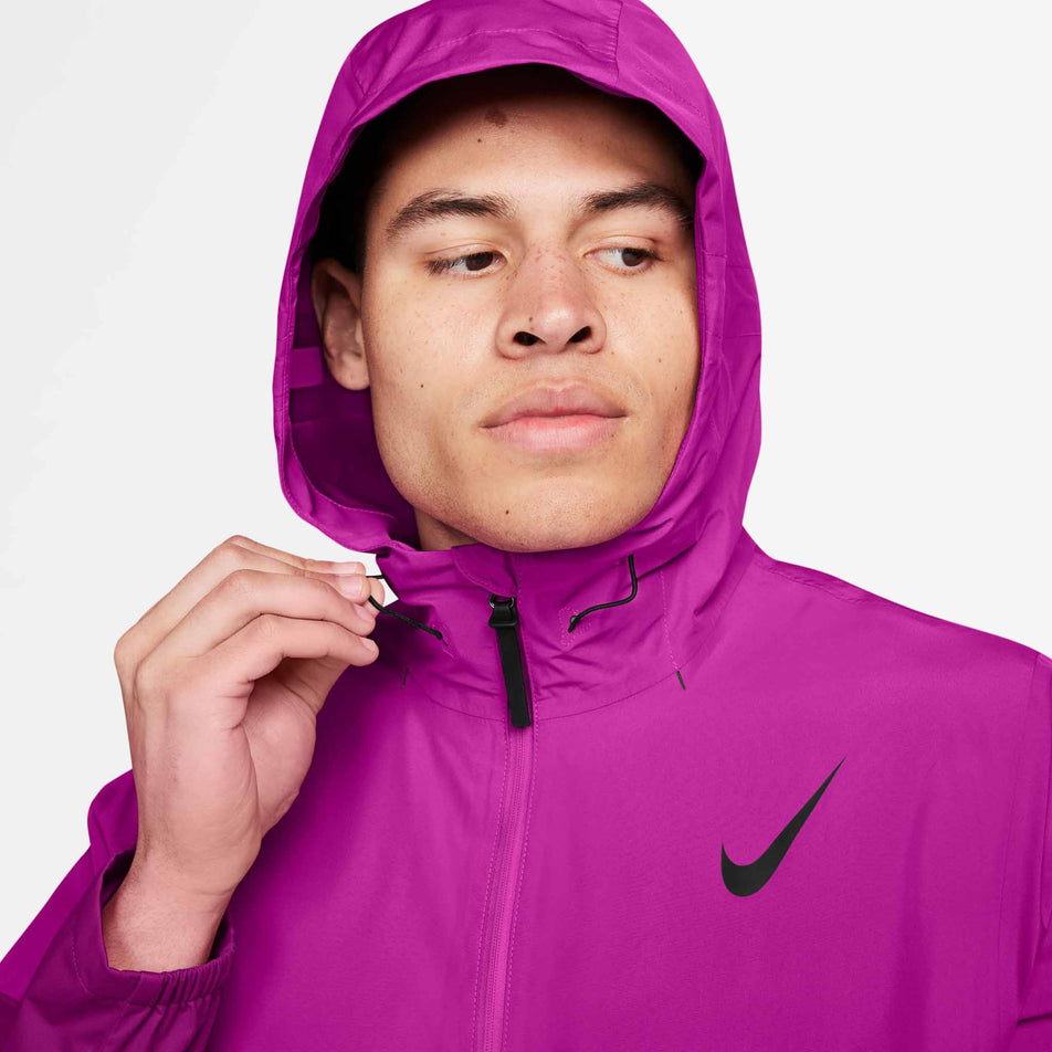 Close-up view of a model with the hood of the Nike Storm-FIT Aeroswift Aerogami Running Jacket in the Vivid Grape/Black colourway up over their head. The rest of the jacket is not visible in the image. (8497739333794)