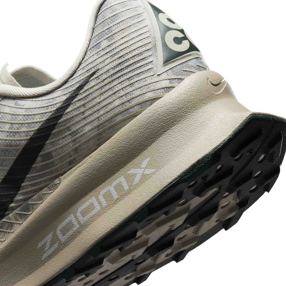 Close-up view of the rearfoot section of the left shoe from a pair of Nike Unisex ACG Ultrafly Trail Racing Shoes in the Spruce Fog/Black Spruce-Sea Glass colourway.