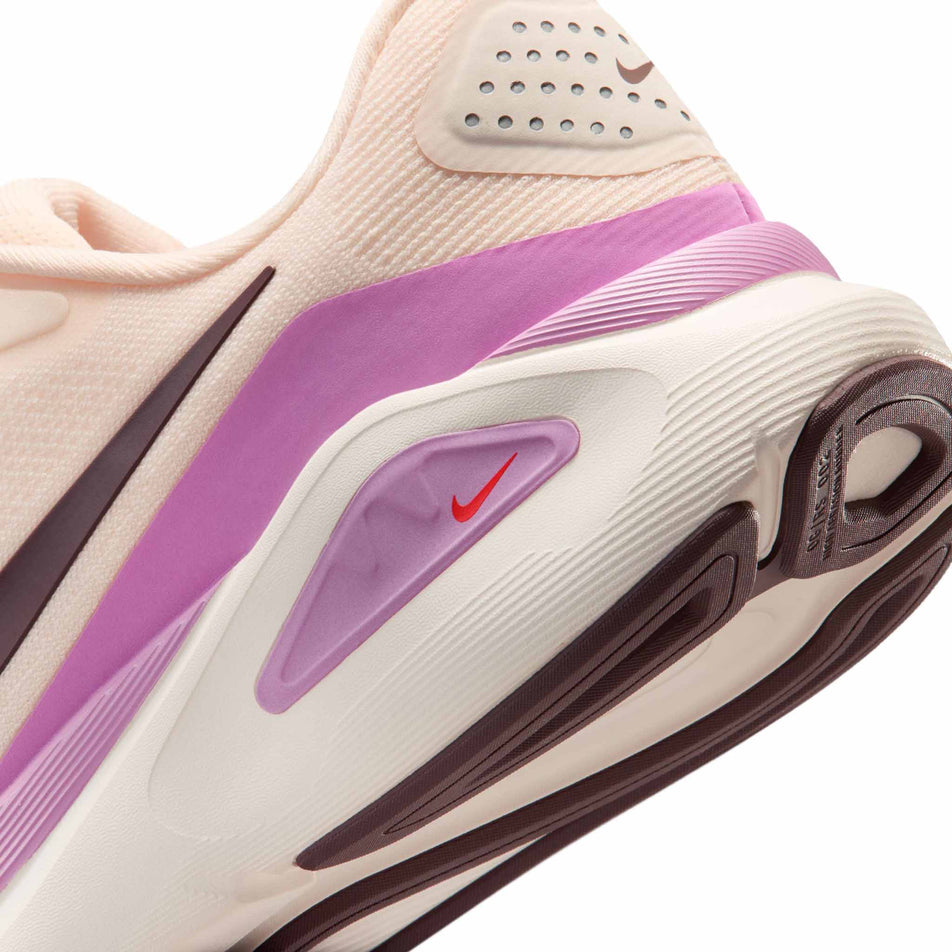 Close-up view of the rearfoot section of the left shoe from a pair of Nike Women's Structure 26 Road Running Shoes in the Chalk/Tattoo-Light Magenta-Orange Pulse colourway.
