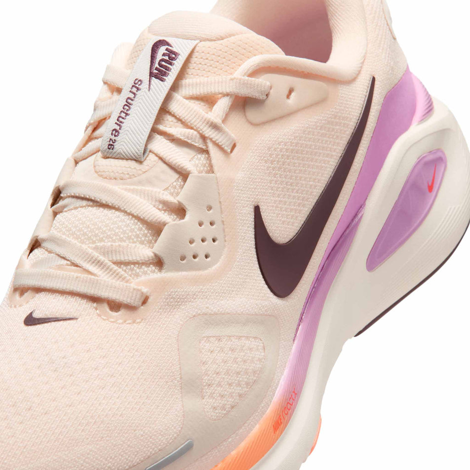 Close-up view of the upper of the left shoe from a pair of Nike Women's Structure 26 Road Running Shoes in the Chalk/Tattoo-Light Magenta-Orange Pulse colourway.