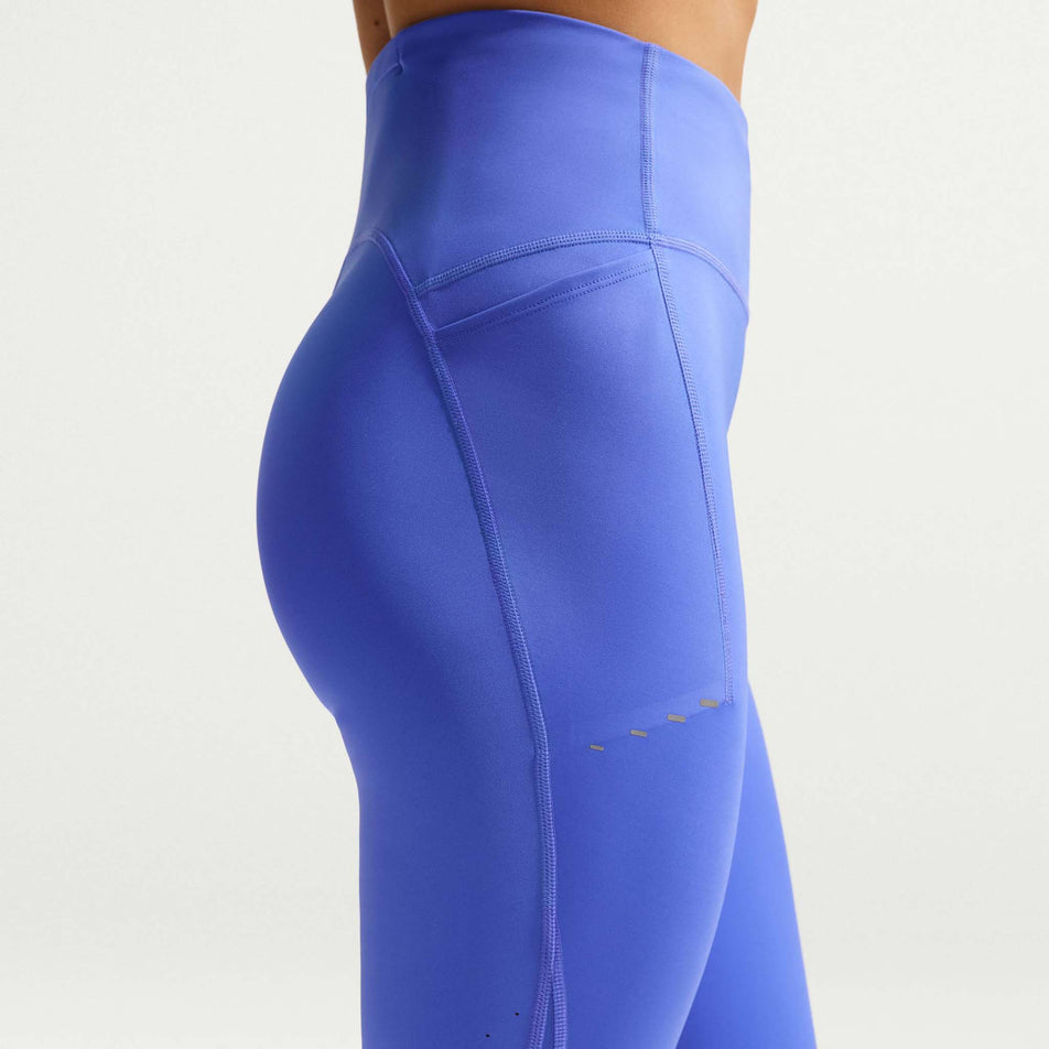 Side view of a model wearing the Nike Women's Swift High-Waisted 7/8 Running Leggings in the Sapphire/Reflective Silver colourway.