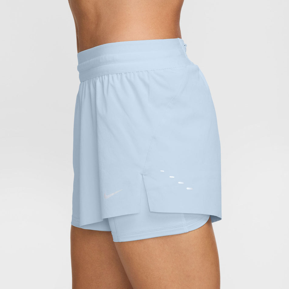 Side view of a model wearing a pair of Nike Women's Swift Dri-FIT Mid Rise 2-in-1 Running Shorts in the Blue Tint/Reflective Silv colourway (8620122800290)