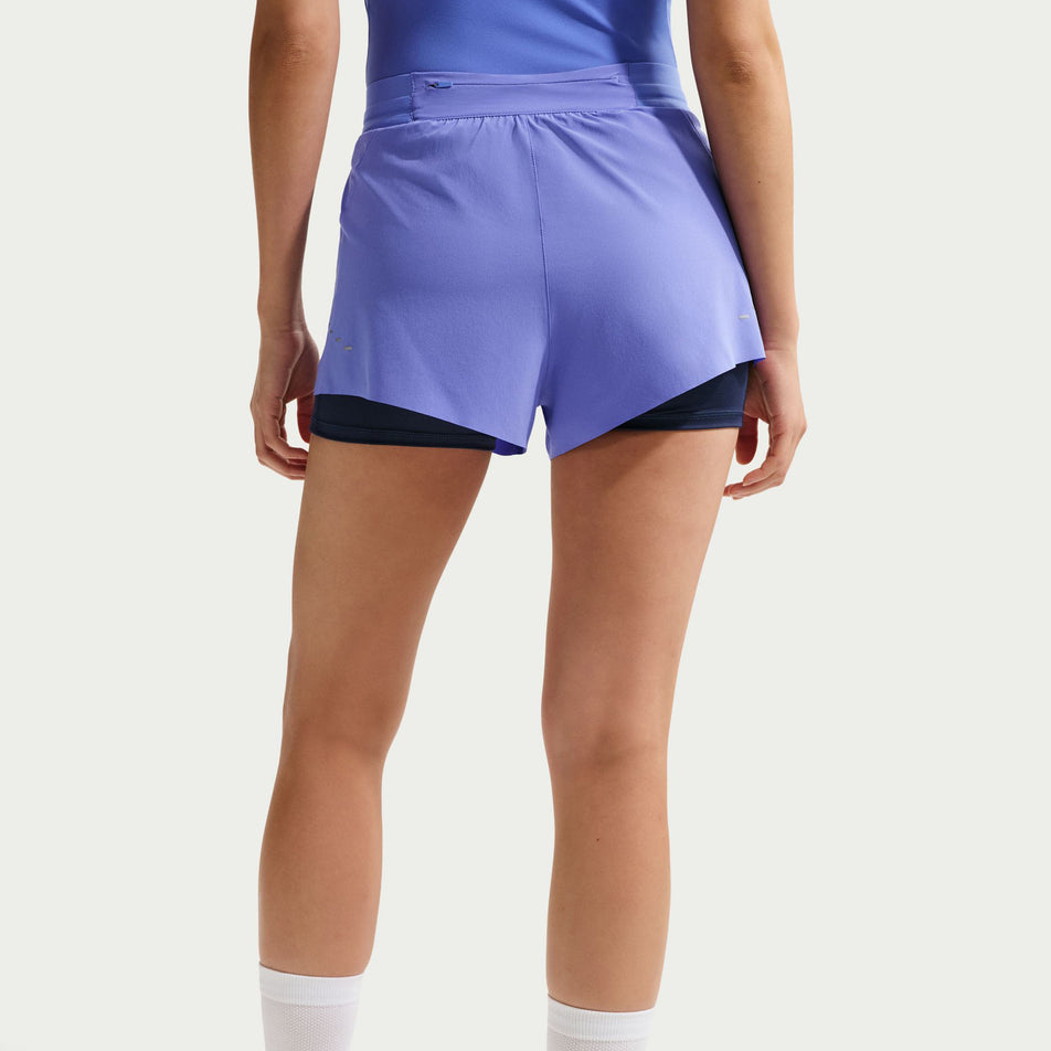 Back view of a model wearing the Nike Women's Swift Dri-FIT Mid-Rise 2-in-1 Running Shorts in the Sapphire/Midnight Navy/Reflective Silver colourway.